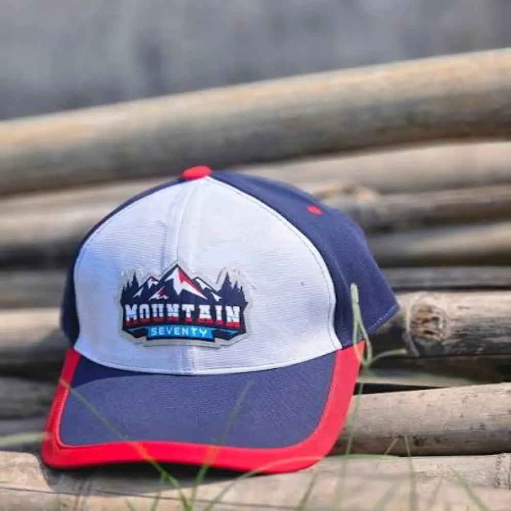 11Sports blue, white, and red Mountain Seventy embroidered sports cap resting outdoors.