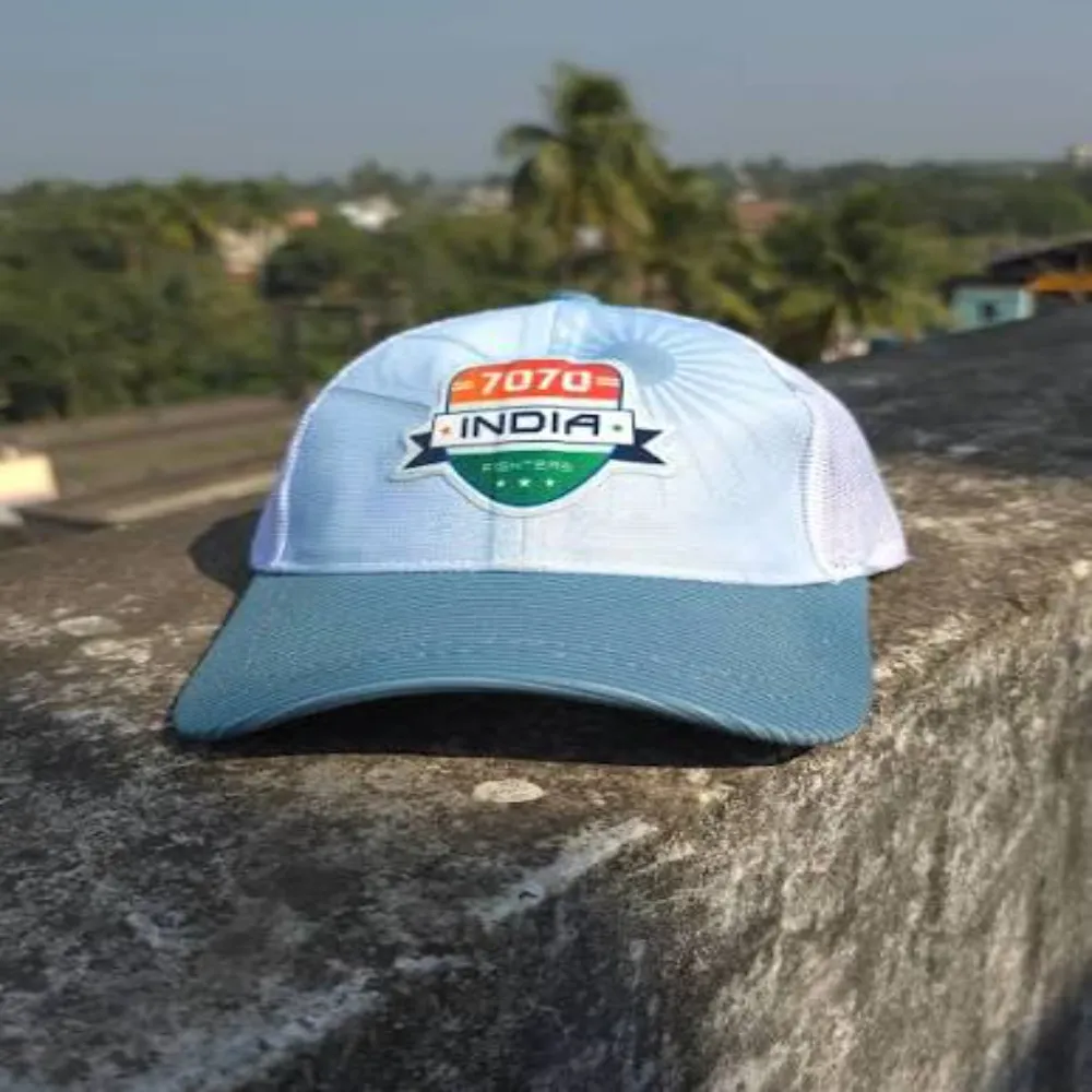 11Sports light blue India 7070 mesh trucker cap resting on a stone ledge outdoors.