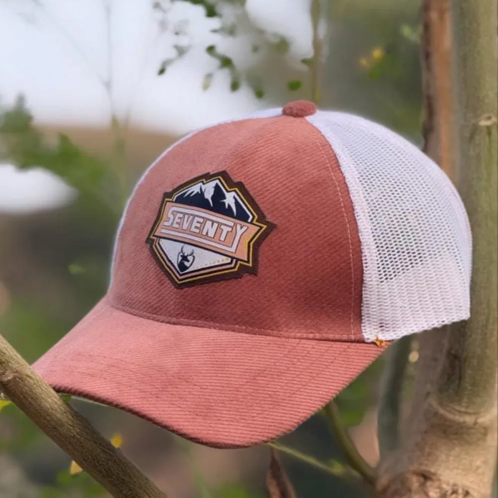 11Sports navy and white cap with an embroidered Mountain Seventy outdoor patch resting on bamboo.