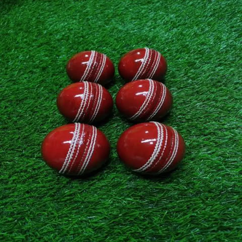 Six glossy 11Sports red synthetic wind balls with white raised seams lined up on turf.