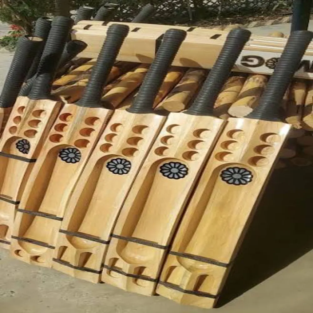 Row of freshly crafted unpainted 11Sports hard tennis cricket bats with laser-engraved floral emblems and ribbed grips.
