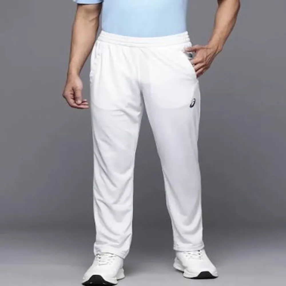Front angle of 11Sports clean white cricket track pants with black oval thigh emblem worn with white trainers.