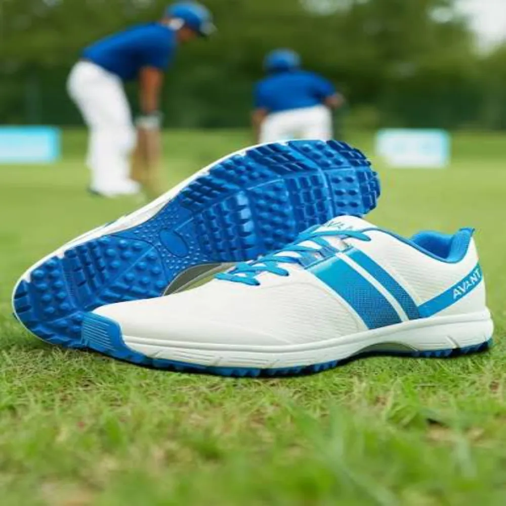 Pair of 11Sports Avant white and blue rubber stud cricket shoes resting on a grass pitch.