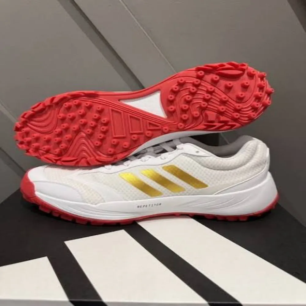 11Sports white mesh turf shoes with metallic gold stripes set on an angled red rubber lug outsole.